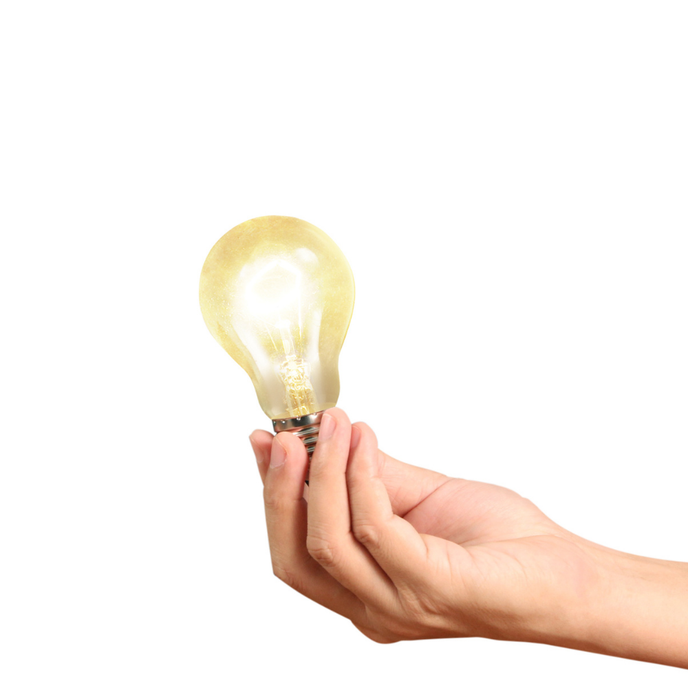 A hand holding a glowing light bulb